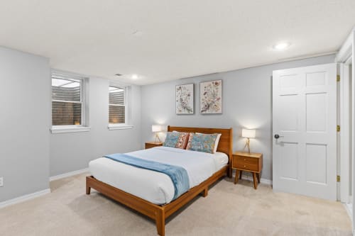 Sink into plush white bedding and let natural light wake you gently in your serene basement retreat.