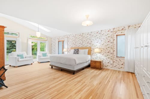 Your spacious master suite features elegant bird-themed wallpaper, gleaming hardwood floors, and a cozy seating area where you can unwind.