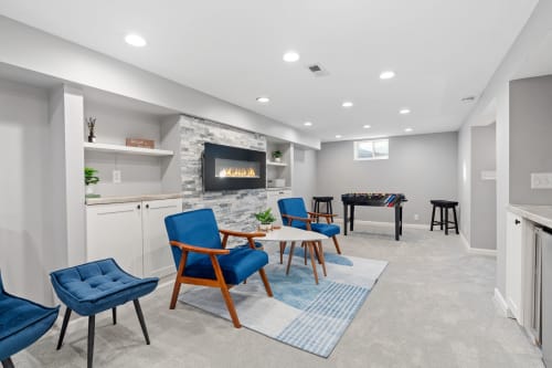 Your stylish basement retreat features mid-century furniture, cozy fireplace, and foosball table for memorable evenings with family and friends.
