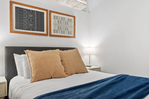 Sink into crisp white linens with plush tan pillows in your peaceful bedroom, where warm lighting creates the perfect ambiance for restful nights.