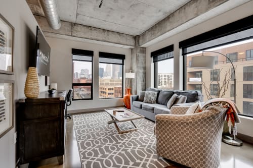 Settle into your stylish urban loft with exposed concrete, plush seating, and stunning city views from floor-to-ceiling windows.