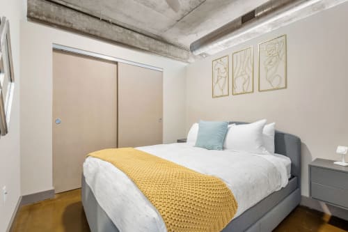 Sink into plush bedding beneath exposed concrete beams in your modern urban retreat, where industrial charm meets cozy comfort.