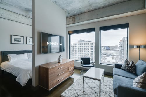 Your modern studio blends comfort with industrial charm, featuring exposed concrete, city views, and thoughtful furnishings for a perfect urban retreat.